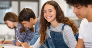 Four high school students sitting in a classroom taking a test.