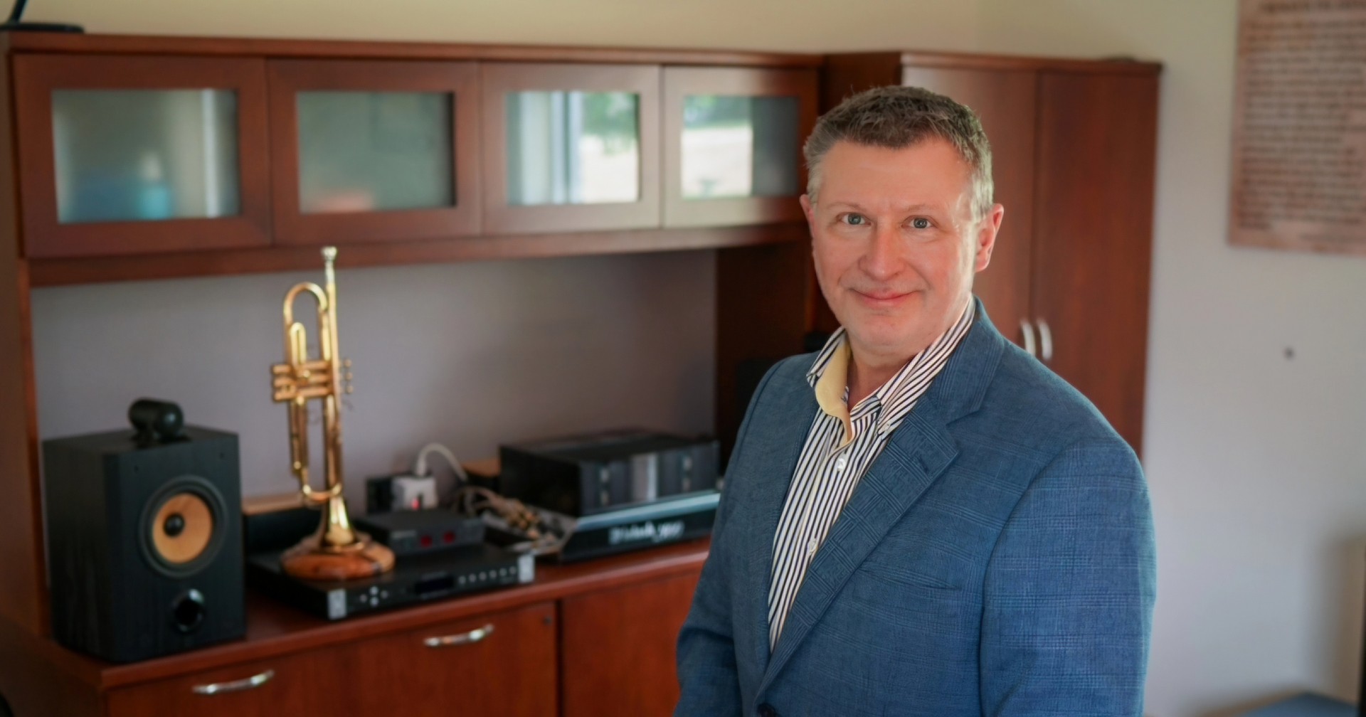 New UD PCS associate dean Mark Clodfelter poses in his office next to his cherished trumpet.