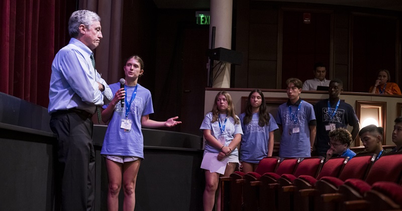 Teenage girl speaks to the governor before a stage, asking for his views.