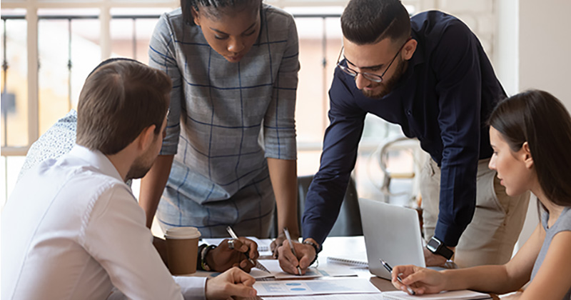 Multiracial corporate business team gather at office table meeting to plan a financial report.