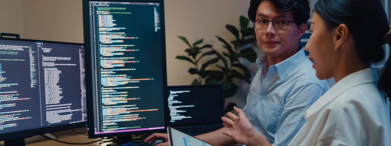 Two coders working in front of two monitors