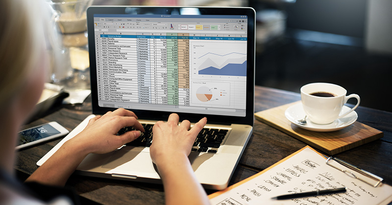 Woman working on a laptop that displays a spreadsheet